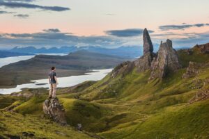 man standing wearing grey shirt and brown pants facing rocky mountain, Top Ten Wonders of the World